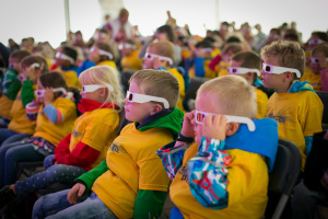 Eine Gruppe von Kindern in gelben T-Shirts und 3D-Brillen auf.